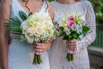 Lgbt lesbian women brides holding bouquets side by side - same sex wedding