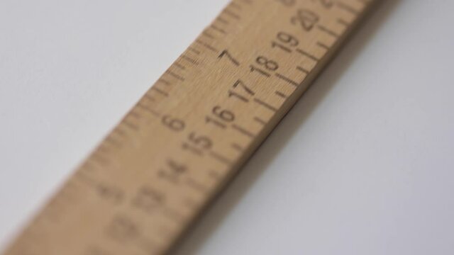 Close up of a measuring stick with scales in inches and centimeters sliding towards the camera.