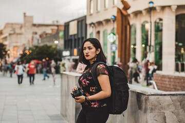 MUJER CON MOCHILA Y CAMARA CAMINANDO EN LUGAR PUBLICO