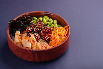 Hawaiian spicy chicken poke bowl with kimchi on purple background
