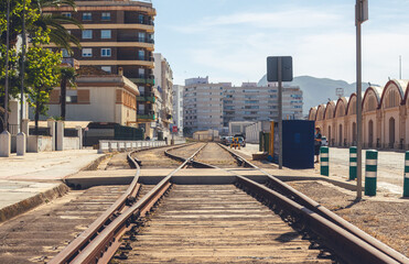 Fototapeta premium Abandoned and rusty train tracks between the buildings of a city.