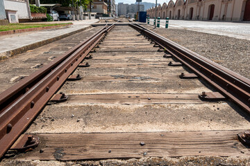 Abandoned and rusty train tracks between the buildings of a city.