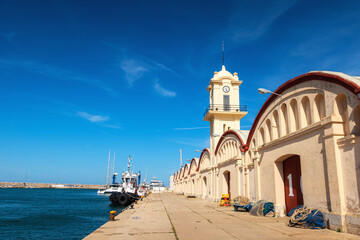 The port of Gandia, with boats and warehouses, in a sunny afternoon