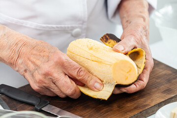 Closeup of a senior woman hands while peeling a ripe plantain © anamejia18