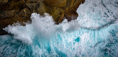 blue-green waves crashing on cliff