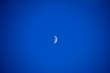 Naklejka na ściany i meble A distant moon in a blue sky in summer