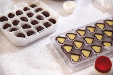 Chocolate shells full of filling of salted caramel cream lying on a table next to homemade chocolate truffles