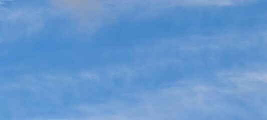 White translucent clouds against the blue sky. On a clear winter day, cirrus clouds are against the background of a clear light blue sky. Clouds are almost invisible against the sky.