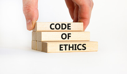 Code of ethics symbol. Concept words 'Code of ethics' on wooden blocks on a beautiful white background. Businessman hand. Business and code of ethics concept. Copy space.