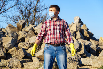 a man works with a pile of stones and broken pieces of concrete, carries construction debris