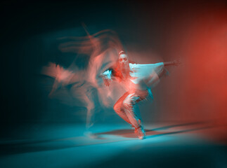 Mixed race young girl dancing in colorful neon studio light. Long exposure. Contemporary hip hop...