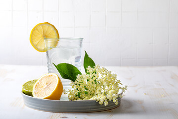 Glass of homemade elderflower lemonade with lemon, lime juice and freshly picked elderberry flowers. Healthy refreshing  mocktail with elderflower cordial syrup