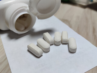 White medical jar, scattered pills in capsules on a sheet of paper.