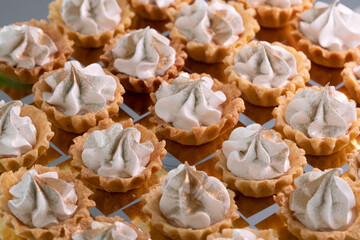 Grupo de pequeños pastelitos de postre decorados con crema y brillantina dorada.