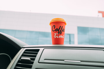 Coffee in the car. Bright orange coffee cup on the car console