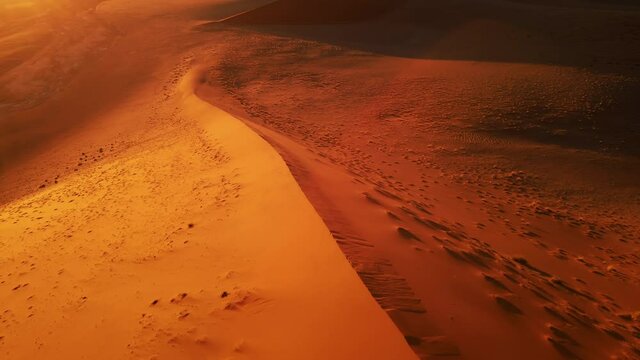Drone shot from close distance to dazzling sand dune. Aerial view of barren wilderness of wide orange desert. Empty massive sand hills in africa. Magnificent natural landscape under clear blue sky