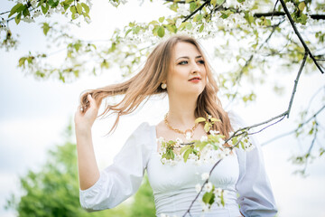 beautiful blonde girl in spring cherry garden