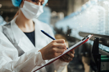 Female worker with protective face mask working in medical supplies research and production factory...