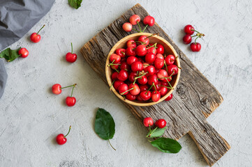 Fresh ripe red cherries in bowl on white stone background, heap of summer fruits concept