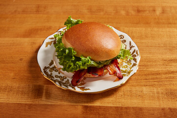 BLT sandwich served on an white ornate plate with gold details on a wooden surface