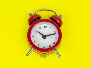 Red alarm clock on yellow background with copy space