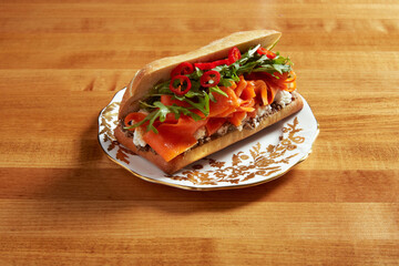 Smoked carrot sandwich served on an white ornate plate with gold details on a wooden surface