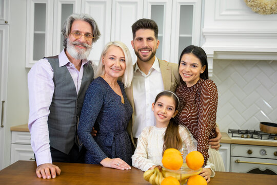 Birthday party. Portrait of big happy multigenerational family father mother and senior grandparents together with cute little child granddaughter posing for camera in stylish kitchen at home