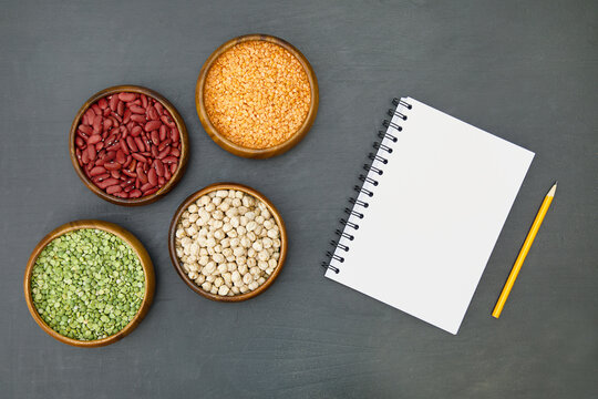 Beans assortment on black background.Leguminous plants. Flat lay of various sources of vegetable protein: beans, lentils, peas, chickpeas, mung bean in bowls. Top view. Copy space on block note.