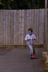 Cute Redhead Boy Riding A Red Scooter On A Path