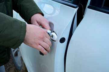 a man opens the car door with a key. one hand holds the key, the other pulls the handle