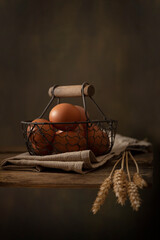 Fototapeta na wymiar Vertical still life composition in rustic style. Eggs, bunch of wheat ears on wooden table
