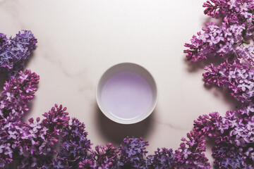 A bowl on a marble background decorated with lilac flowers