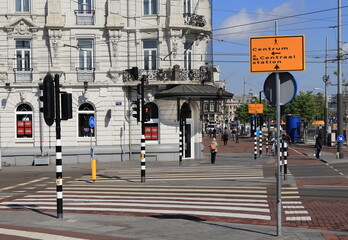 Amsterdam Street View with People and Yellow Directional Signs