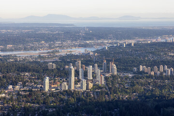 Aerial View from Airplane of Residential Homes and Buildings in a modern city during sunny evening. Taken in Coquitlam, British Columbia, Canada.