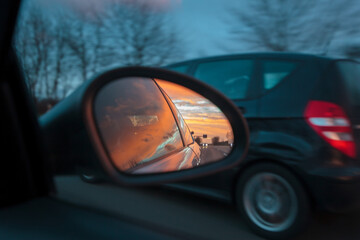 Sunset Landscape Reflected in Car Wing Mirror at Dusk
