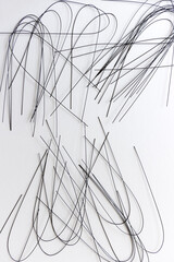 multiple crafting wire (painted black) bent and scattered on white - photographed from above in flat lay composition