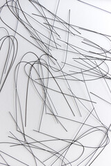 multiple crafting wire (painted black) bent and scattered on white - photographed from above in flat lay composition