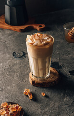 Iced coffee with milk in a tall glass on a dark background. Selective focus