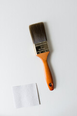 synthetic long bristled paint brush with a orange brown shiny wooden handle isolated on white - with a square piece of paper for text