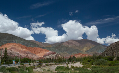 The colorful hills. Aerial view of the beautiful Andes mountains in Purmamarca, Jujuy, Argentina. The minerals and rock texture under summer blue sky with clouds.