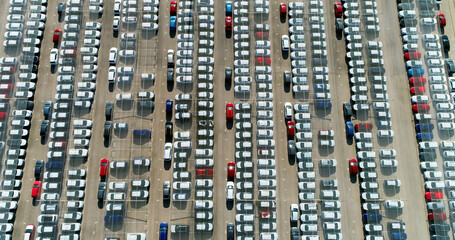 Cars parked in a parking lot under the sunlight. They are protected by a transparent plastic roof - aerial view with a drone 4K