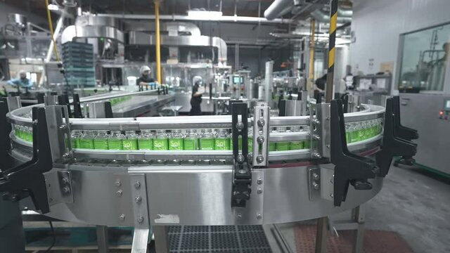Robotic factory line for processing and bottling juice bottles. Production automation line. Beverage factory interior.
