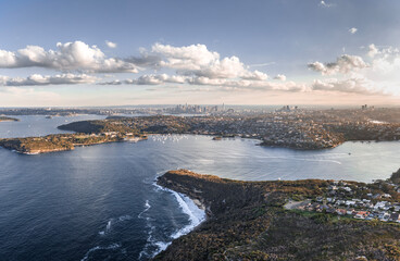 High angle aerial drone view of Balmoral Beach and Edwards Beach in Mosman, Sydney, New South Wales, Australia. CBD, North Sydney and Chatswood in background left to right. Grotto Point in foreground.