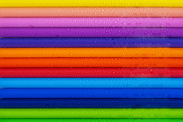 Multicolored pencils with water drops on wooden table, top view, selective focus
