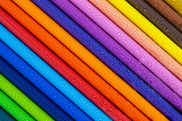 Multicolored pencils with water drops on wooden table, top view, selective focus