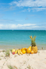 Tropical Fruits at the beach under blue sky, Pineapple, Papaya, Passion Fruits, Banana, Orange