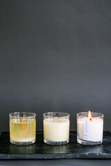 Three candles stand on the table on a gray background.