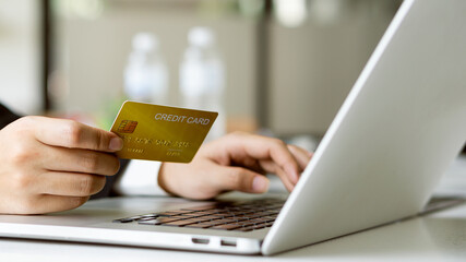 Young women hold credit cards and use laptop computers to shop online, e-commerce, internet banking, spend money, work from home.