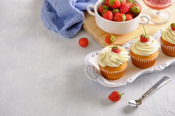 Tasty and fragrant cupcakes with strawberries and gentle cream on a white background