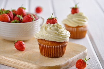 Tasty and fragrant cupcakes with strawberries and gentle cream on a white background